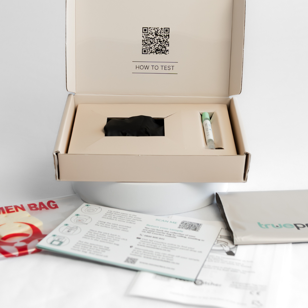 Open box containing a bowel cancer screening FIT test kit with instructions and a pouch on a white surface.