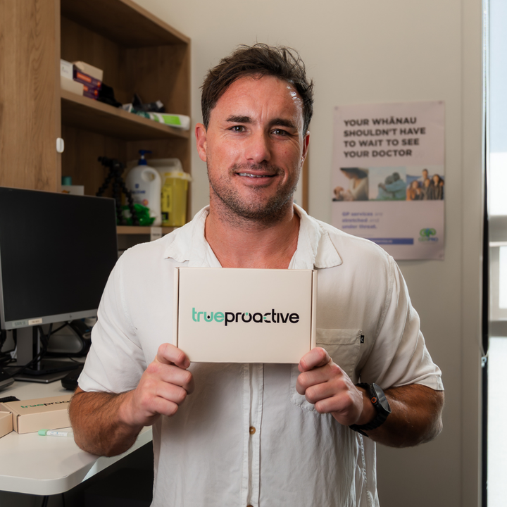 Dr. Clive Price holding a 'true proactive' bowel cancer screening FIT Test available to order at trueproactive.co.nz